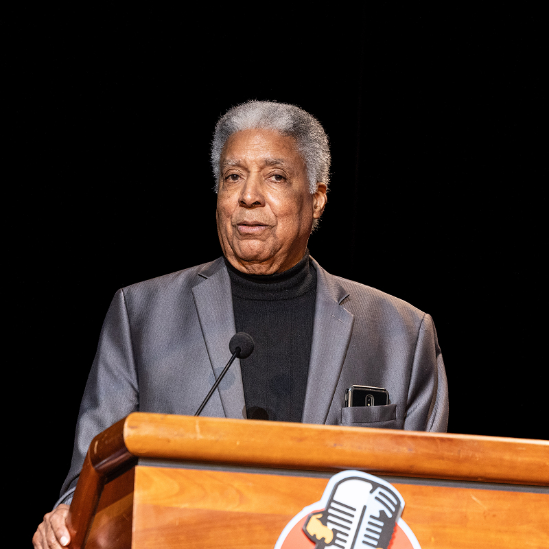 Art speaks at a podium