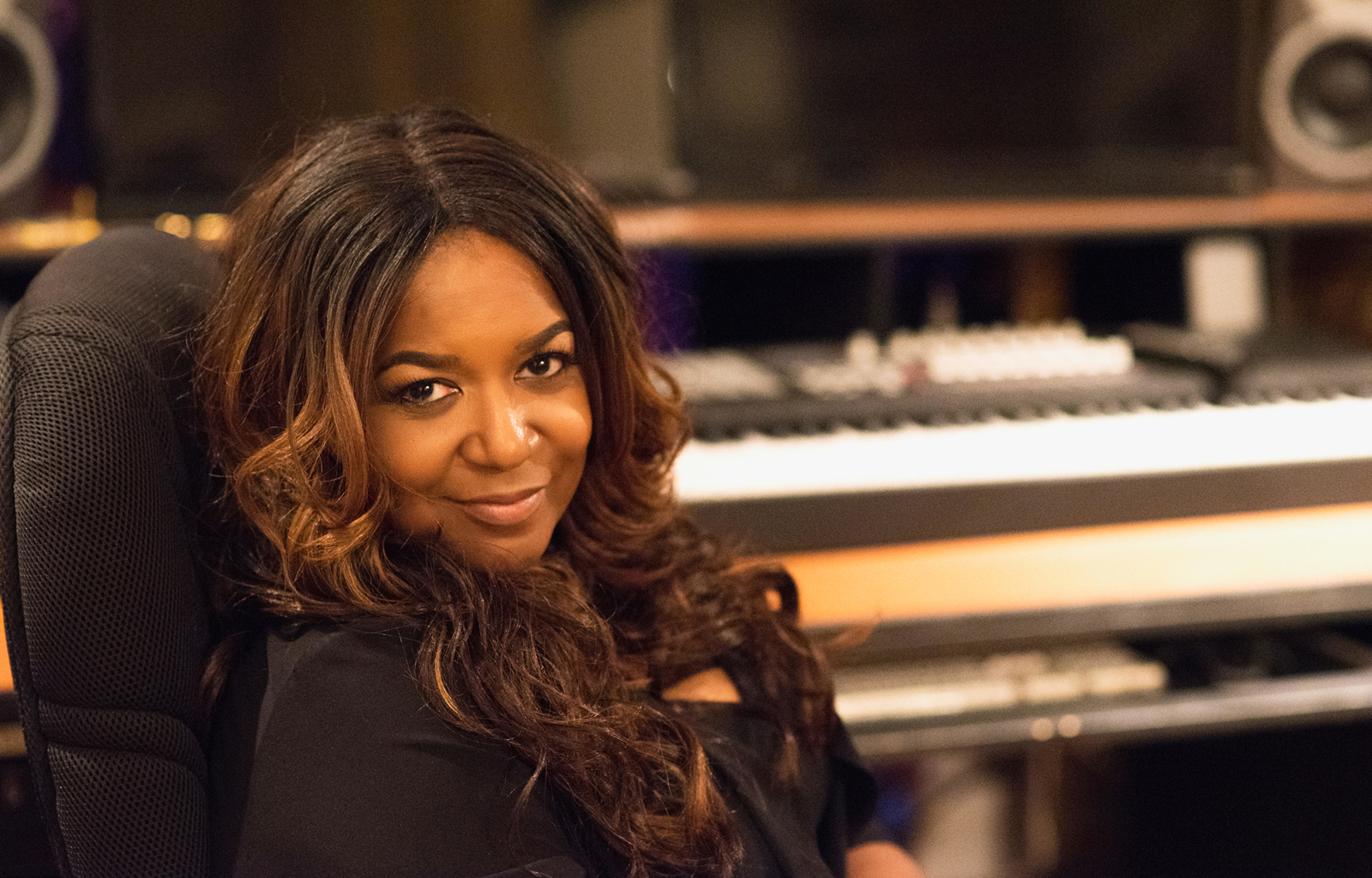 Wendy smiles at the camera, reclining in a chair in a recording studio